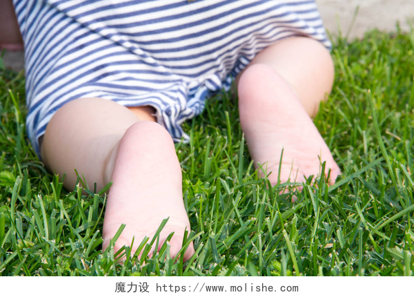 可爱的婴儿在绿草上爬行可爱的婴儿在绿草上爬行。后视图。主要关注婴儿脚.